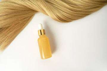 A natural essential oil or serum for hair care with vitmin C lying on a white table. Hair care and...