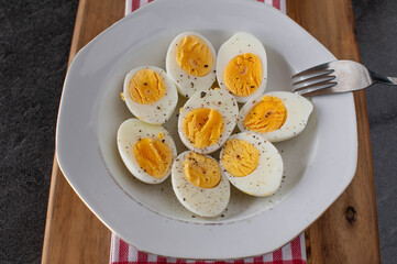 Half boiled eggs with ground pepper and salt on a plate