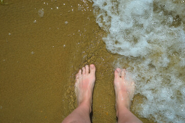 women's feet on the sandy seashore. summer vacation, sun, sea, clean beach. background for the...
