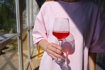 A glass of red wine in the hands of a girl relaxing in a restaurant. Tasting of alcoholic beverages. Summer rest. Romantic evening aperitif. Close-up of a glass of wine. Enjoy the moment 

