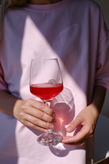 A glass of red wine in the hands of a girl relaxing in a restaurant. Tasting of alcoholic beverages. Summer rest. Romantic evening aperitif. Close-up of a glass of wine. Enjoy the moment 
