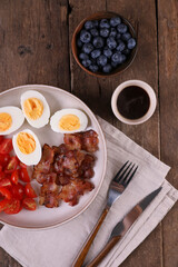 Breakfast with bacon, eggs and coffee on a wooden table