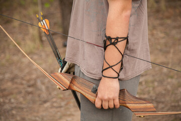 Close up of teen guy holding recurve bow and arrows