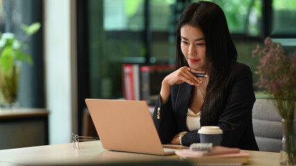 Elegant millennial businesswoman watching online webinar, reading email on her laptop computer