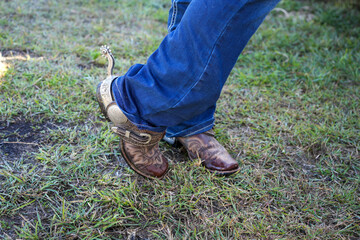 Cowboy boots and silver spurs worn by female in blue jeans - obrazy, fototapety, plakaty