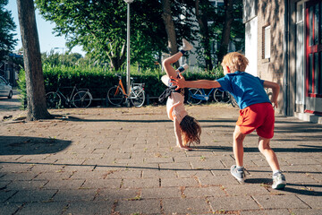 children playing on the neighborhood sidewalk - girl doing cartwheel