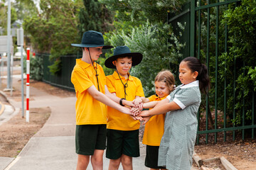 Four primary school kids playing together before school, stacking hands