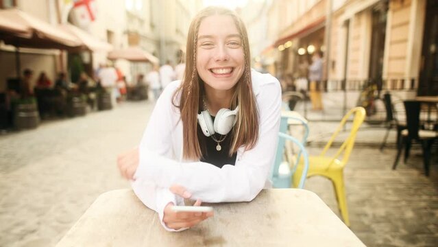 Happy positive young caucasian woman smiling while listening to his interlocutor in the city cafe. Talk conversation during first date in restaurant from first-person view. 
