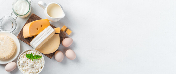 Different types of cheese, cottage cheese, sour cream and eggs on a gray background. A set of dairy products. Top view, copy space