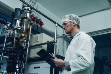 Naklejka na ściany i meble Scientist holding paper board and checking rotational vaporizer during CBD oil extraction, hemp oil extraction process.
