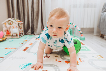 A little boy is playing with a ball on the mat at home. The concept of children's development, sports, education and creativity at home