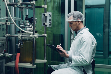 Scientist holding paper board and checking rotational vaporizer during CBD oil extraction, hemp oil extraction process.