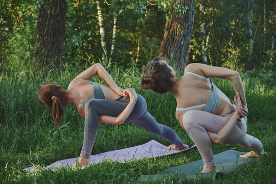 Yoga personal trainer teaching young woman niralamba parsvakonasana outdoor