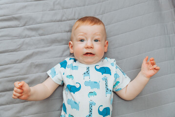 a small child is lying alone on a wide bed. the kid is looking at the camera with his legs tucked under him. top view