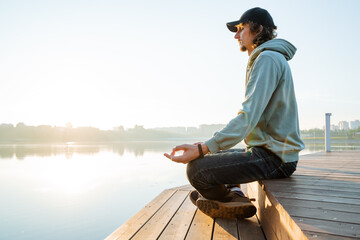 Meditation in silence the guy sits in the lotus position, hands folded on his knees fingers in chinmudra, morning yoga at dawn of the day, calm inside the body Zen