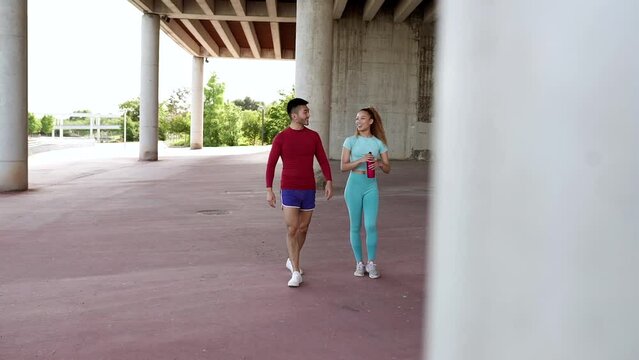 two young multiracial workout buddies asian man and hispanic woman, wearing sportswear, walking in park, healthy lifestyle.