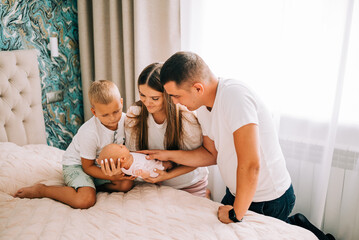 Obraz na płótnie Canvas Newborn baby with happy parents and brother. Happy family. Healthy newborn baby with mom and dad. Mother, father and infant baby. Cute Infant girl and parents