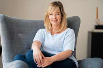 Attractive mature woman sitting in an armchair at home