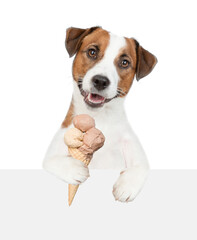 Jack russell terrier puppy holds ice cream above empty board. isolated on white background