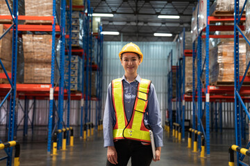 Portrait of female supervisor standing and holding laptop in warehouse with looking at camera.