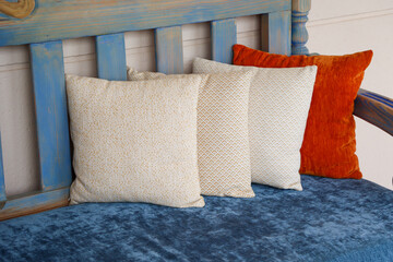 Vier farbige Kissen stehen auf einer Holzbank.