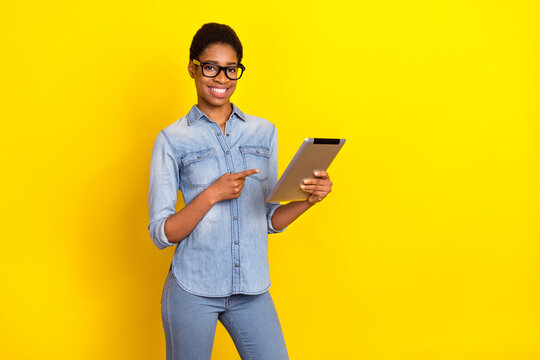 Photo of positive person indicate finger tablet gadget offer promotion isolated on yellow color background