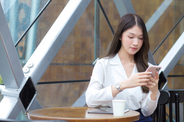 Obraz premium Professional young Asian businesswoman with long hair while working outside the office is using a smartphone to do business with a partner.