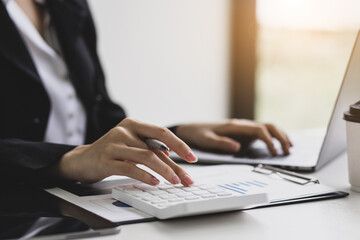 Business woman, a financial advisor in the office, prepares accounting by using a calculator to calculate and allocate a budget.