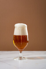 Light beer with overflowing  foam in glass and snacks copy space