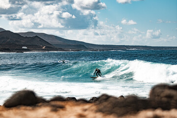 Wild rocky coastline of surf spot La Santa Lanzarote, Canary Islands, Spain. Surfer riding a big...
