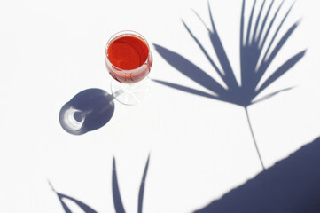 glass with a cold drink and shadows from palm leaves