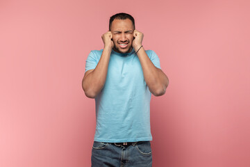 Young african americn man having sore ear, suffering from otitis, touching his inflamed head and closed eyes, free space