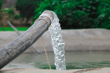 Pumping water out of plastic pipe into the ground,Water from a well filled a pond for irrigation,Irrigation water from the source,Water flow from large pump tube in Farm,being flush out a heavy tube,