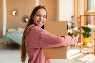 Delivery and shopping. Excited teen customer girl hugging cardboard box and smiling, receiving new...
