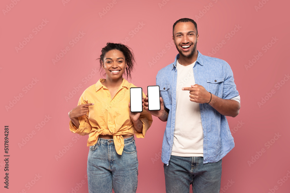 Poster use this new application. happy black couple holding 2 smartphones in hands and pointing at empty sc