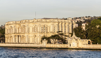 Beylerbeyi Palace on the coastline of Bosporus strait in golden hour. View from touristic boat on Bosporus. Istanbul, Turkey