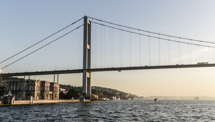 Beylerbeyi Palace under 15 July Martyrs Bridge at sunset. View from touristic boat on Bosporus. Istanbul, Turkey