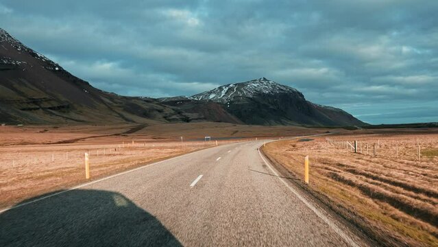 View of empty road leading towards mountain range in Iceland. Beautiful endless road during sunset. Scenic view of diminishing highway in a valley in the middle of Iceland.
