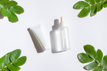 Cosmetic bottles with green leaf on white background
