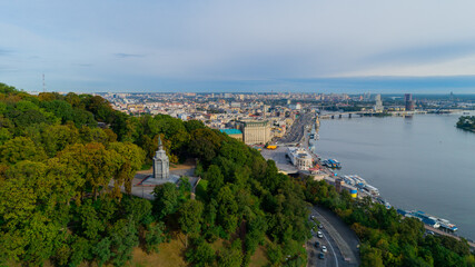 Fototapeta na wymiar Aerial view monument to Volodymyr Velykyi on Volodymyr Hill in middle trees. Volodymyr Great. Drone shot river station, postal area on a sunny spring day. Dnipro river. Capital of Ukraine