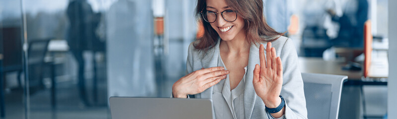Confident deaf businesswoman communicating in video call with client at workplace in modern office.
