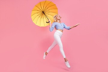 Full length photo of pretty dreamy girl dressed blue top jumping high holding umbrella empty space...