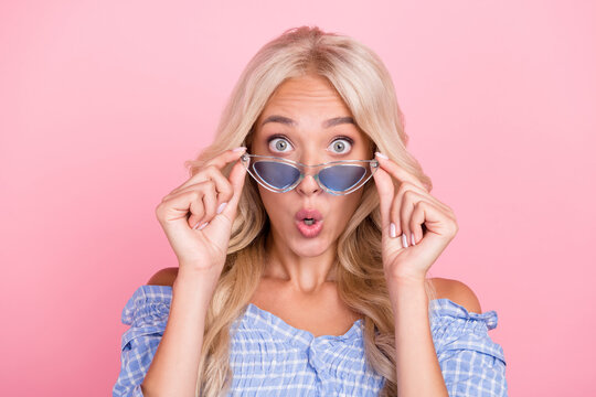 Photo of charming impressed girl dressed blue top hands arms dark eyewear big eyes isolated pink color background