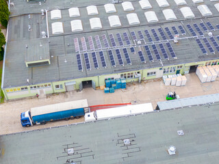 Aerial view of goods warehouse. Logistics center delivery in industrial city zone from above. Aerial view of trucks loading at logistic center