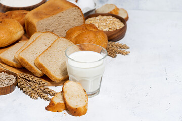 glass of milk, assortment of fresh bread and ingredients on white background, top view
