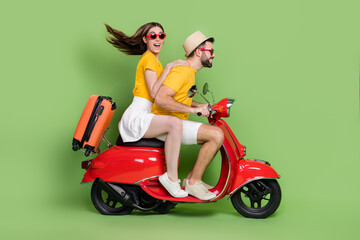 Fototapeta na wymiar Full length profile portrait of two excited partners drive moped adventure isolated on green color background