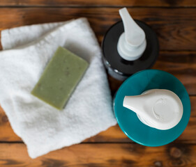 Obraz na płótnie Canvas olive soap on a towel and shampoo bottles on a wooden background.