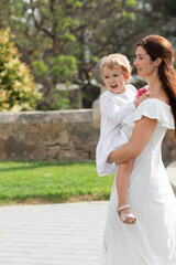 Woman in white dress carrying toddler daughter with flowers in Valencia.