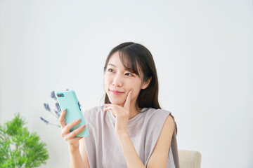 リビングでスマホを持って想像する女性