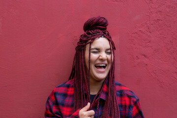 Portrait smiling young woman with red dreadlocks wearing a red checkered shirt